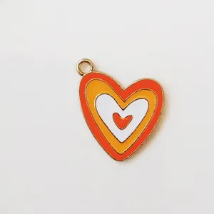 Macro shot of tiered heart pendant with colorful enamel drips and golden metal loop