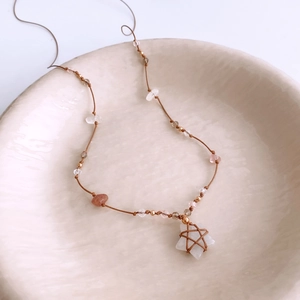 Detail of pink crystal star pendant necklace with woven cord and elegant beads