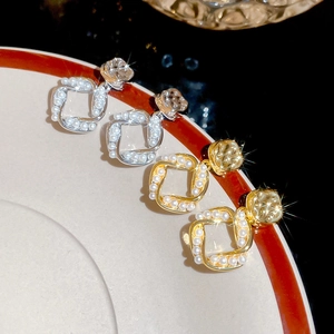 Detail of square gold and silver earrings with small pearls and large clear crystals