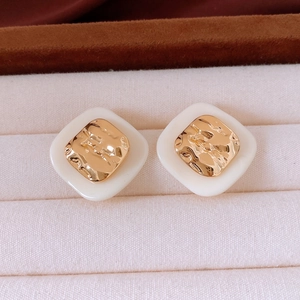 Nahaufnahme von quadratischen Acetat-Ohrringen mit Goldbeschichtung auf Samt-Schmuckkästchen