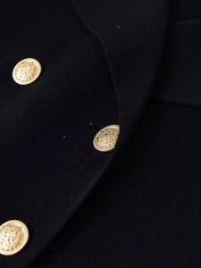 Close-up of black knit texture and decorative gold lion head embossed metal buttons