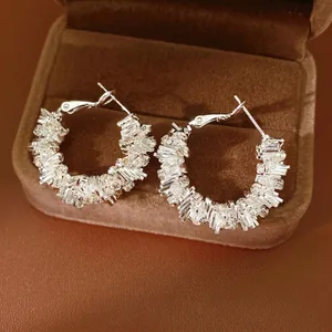 Irregular geometric hoop earrings with sparkling cubic zirconia on brown velvet