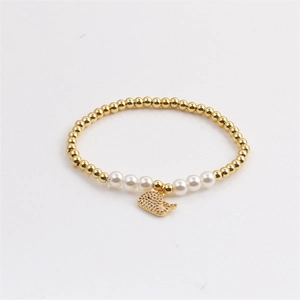 Elastic gold bead bracelet with white pearls and a sparkling dolphin charm for women
