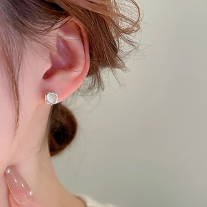 Close-up of minimalist square faux moonstone stud earring with silver metal base on model