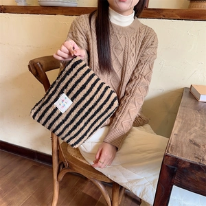 Detail of soft plush brown striped makeup bag featuring colorful textile patch on side