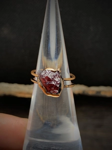 Macro shot of an irregular dark red raw gemstone ring with a gold double-layer bezel setting