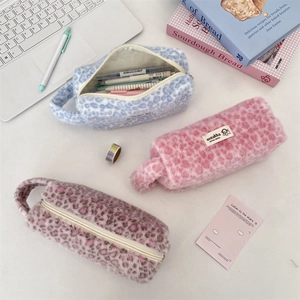 Detailed view of leopard print plush cosmetic pouches in blue, pink and purple with zippers