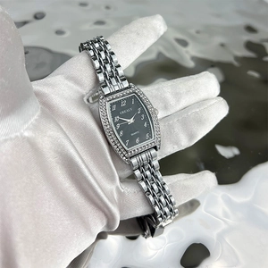 Detailed close-up of a silver tonneau quartz watch with a diamond-set bezel and black dial