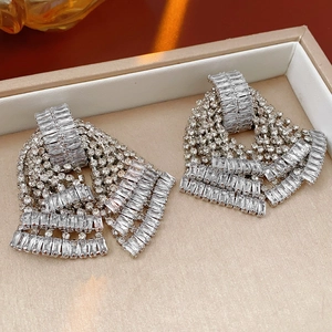 Macro shot of silver bowknot tassel earrings with rhinestones in a display box