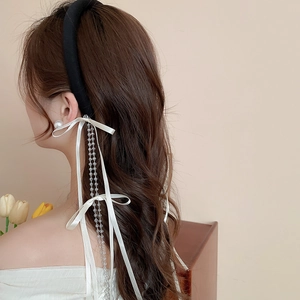 Detail of fabric bow headband with elegant white satin ribbons and beaded tassels