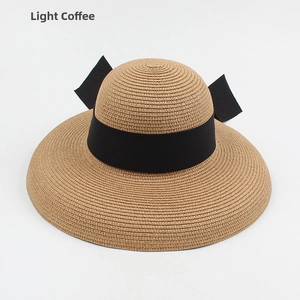 Detail of light coffee straw sun hat featuring tight spiral weave and black satin bow