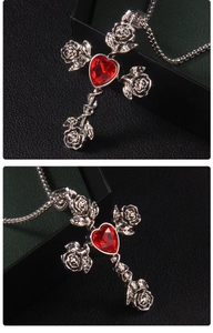 Detail of silver cross necklace with red heart gemstone and rose relief carving