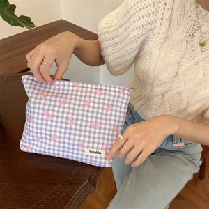 Detail of purple plaid pouch featuring pink bow accents and a sturdy metal zipper