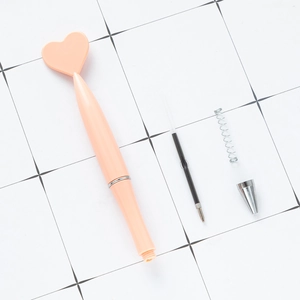 Disassembled pink heart-shaped ballpoint pen showing internal ink refill and spring