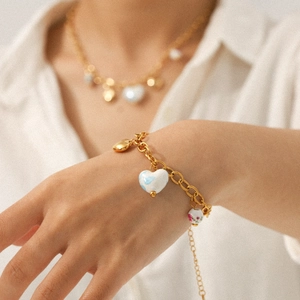 Bracelet chaîne dorée avec pendentifs en céramique en forme de cœur et motifs floraux bleus