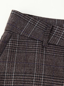 Gros plan du pantalon à carreaux marron montrant la couture de taille et le tissu tissé
