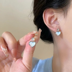 Close-up of heart-shaped earring featuring blue mother of pearl inlay and zircon detail