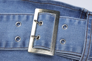 Detail of blue denim fabric with orange stitching and silver double-pin buckle