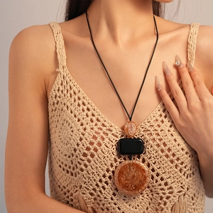 Detail of bohemian resin sweater necklace featuring amber and black geometric pendants