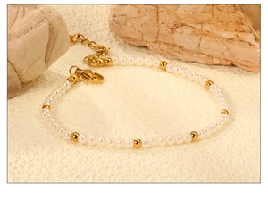 Detail of white pearl beaded bracelet with gold lobster clasp and adjustable chain