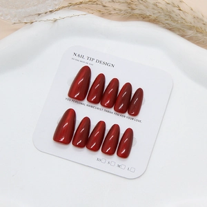 Deep red cat-eye press-on nails in long almond shape on a minimalist display card