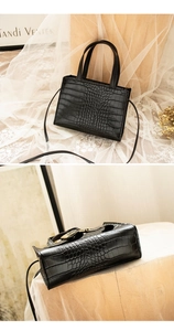 Detailed view of black crocodile pattern crossbody bag with gold hardware and bottom studs