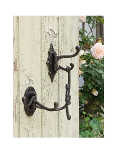 Close-up of vintage cast iron triple swivel wall hook in rustic bronze on a green door