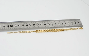 Détail d'un bracelet en acier inoxydable doré 18K mesuré avec une règle en acier graduée