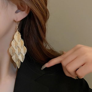 Close-up of golden tiered leaf tassel earrings on model showing stylish vintage texture