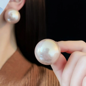 Close-up of large round pearl earrings with elegant champagne pink luster and gloss finish