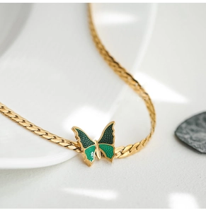 Detail of 18K gold plated anklet featuring a green butterfly pendant and flat weave chain