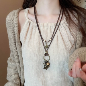 Detailed shot of retro wax cord necklace with bronze star and ring pendant on a model