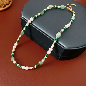 Close-up of pearl necklace with malachite and shell beads on leather jewelry box