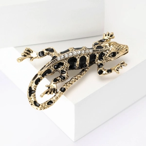 Golden lizard brooch with black enamel and crystals on white geometric blocks