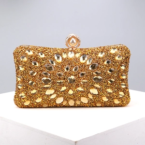 Detail of gold evening clutch bag featuring yellow rhinestones and pearl top clasp