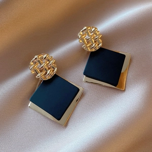 Chic geometric gold earrings with black square sequins on champagne silk background