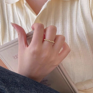 Detail of beaded 925 sterling silver ring in gold finish worn with a cozy knit sweater
