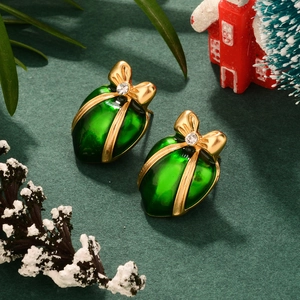Macro shot of green Christmas gift box earring with golden bow and sparkling crystal