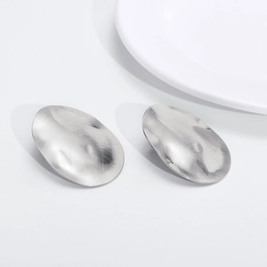 Macro shot of silver metal oval earrings featuring a unique hammered textured finish