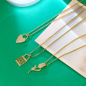 Détail de chaînes dorées avec pendentifs serrure coeur et tulipe ornés de zircons