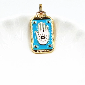 Detail of gold Hamsa hand pendant with blue enamel, eye design, and FORTUNE engraving