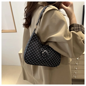 Detail of dark grey crescent hobo bag with textured pattern and silver bow accessory