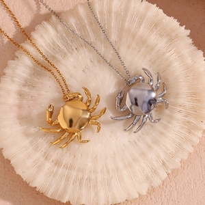Detail of crab pendants in gold and silver finish on white coral background