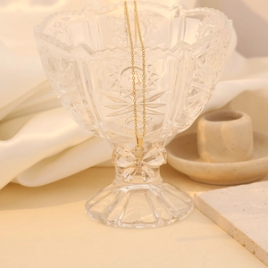 Detailed shot of a butterfly pendant with clear crystals and gold-plated chain over silk
