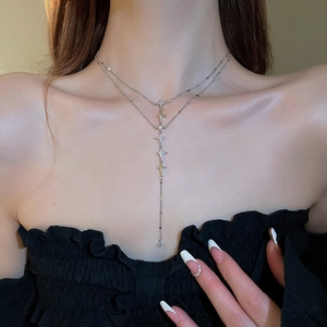 Close-up of double-layer stainless steel star necklace with tassel on a female neck