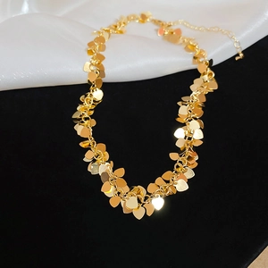 Dettaglio della collana dorata con frange a cuore che mostra strati e texture