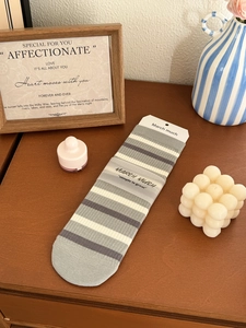 Close-up of striped mid-calf socks in grey and white with branded paper packaging