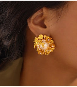 Gros plan de boucles d'oreilles baroques vintage avec perle et détails de fleurs dorées