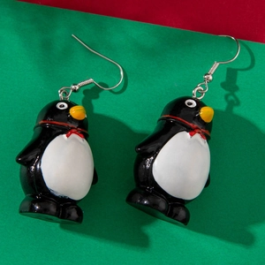 Close-up of cartoon penguin earrings with red bowties on a festive colored background