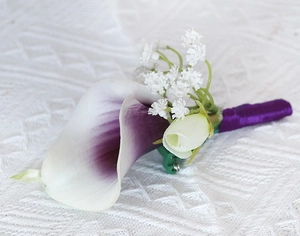 Detail of white and purple calla lily boutonniere with baby's breath and satin stem